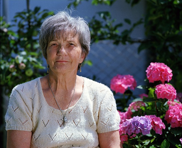 Edlerly woman sitting with flowers.