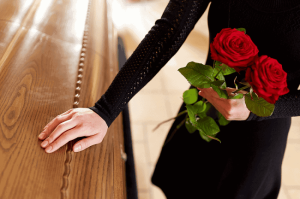 A woman standing at a coffin with flowers to illustrate what heirs should know about probate and inheritance in NC