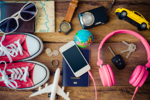 Image of summer items, including travel shoes, a passport, car, airplane, headphones, a phone, and glasses to illustrate the idea of an Estate Planning Checklist summer