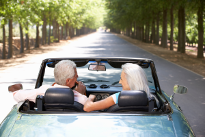 Photo of an older couple driving in a convertible to illustrate the idea of pre-travel estate planning