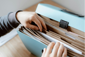 A photo of a person looking for papers in a filebox. This illustrates understanding fiduciary duties in estate planning.