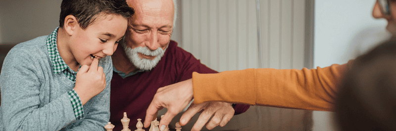 Image of a grandfather playing chess with his grandson. This is to illustrate the people who benefit from revocable living trusts in Raleigh, Durham, Chapel Hill, The Triangle, and throughout North Carolina.